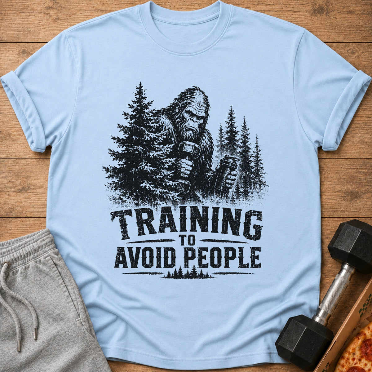Bigfoot with weights and shaker bottle, text "TRAINING TO AVOID PEOPLE".
