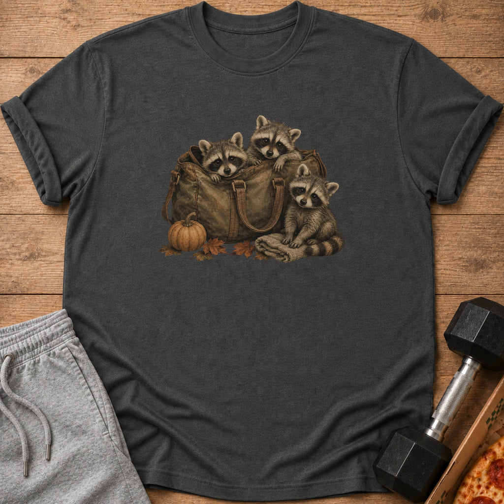 Three raccoons peek out of a duffel bag with a pumpkin and leaves.