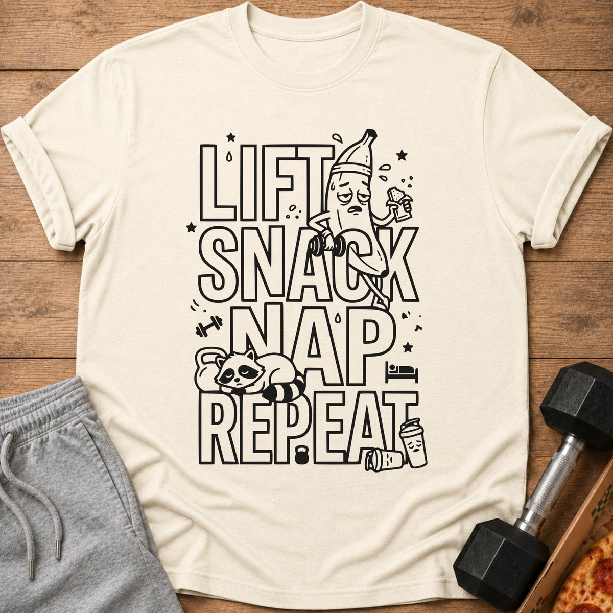 Shirt with "Lift Snack Nap Repeat" text and cartoon graphics of a banana, raccoon, and coffee.