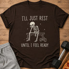 Brown t-shirt with a skeleton sitting on a bench with text: "I'LL JUST REST UNTIL I FEEL READY".