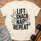 Shirt with "Lift Snack Nap Repeat" text, featuring cartoon banana and raccoon.