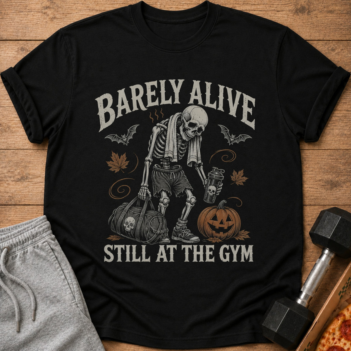 Black t-shirt with skeleton graphic, text "BARELY ALIVE STILL AT THE GYM".