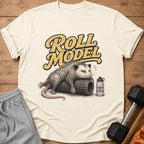 T-shirt graphic of an opossum on a foam roller with text "Roll Model" and water bottle.