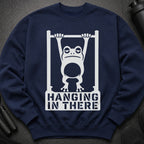 Navy sweatshirt with white graphic of a frog hanging from bars, saying "Hanging In There".