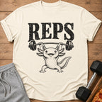 Axolotl lifting weights with "REPS" text on a cream t-shirt.