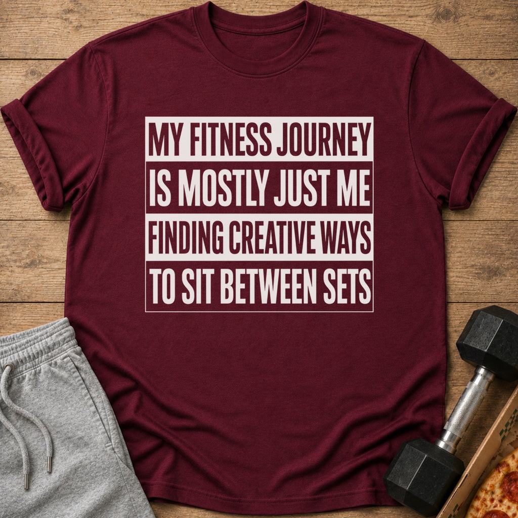 Maroon t-shirt with white text "My Fitness Journey Is Mostly Just Me Finding Creative Ways To Sit Between Sets".