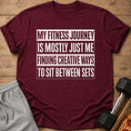 Maroon t-shirt with white text "My Fitness Journey Is Mostly Just Me Finding Creative Ways To Sit Between Sets".