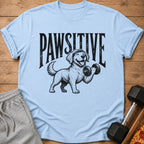 Light blue t-shirt with a dog lifting a dumbbell and the text "PAWSITIVE".