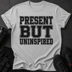Gray t-shirt with distressed black text "PRESENT BUT UNINSPIRED".