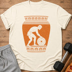T-shirt with orange illustration of ancient Greek athlete lifting weight within a vase.
