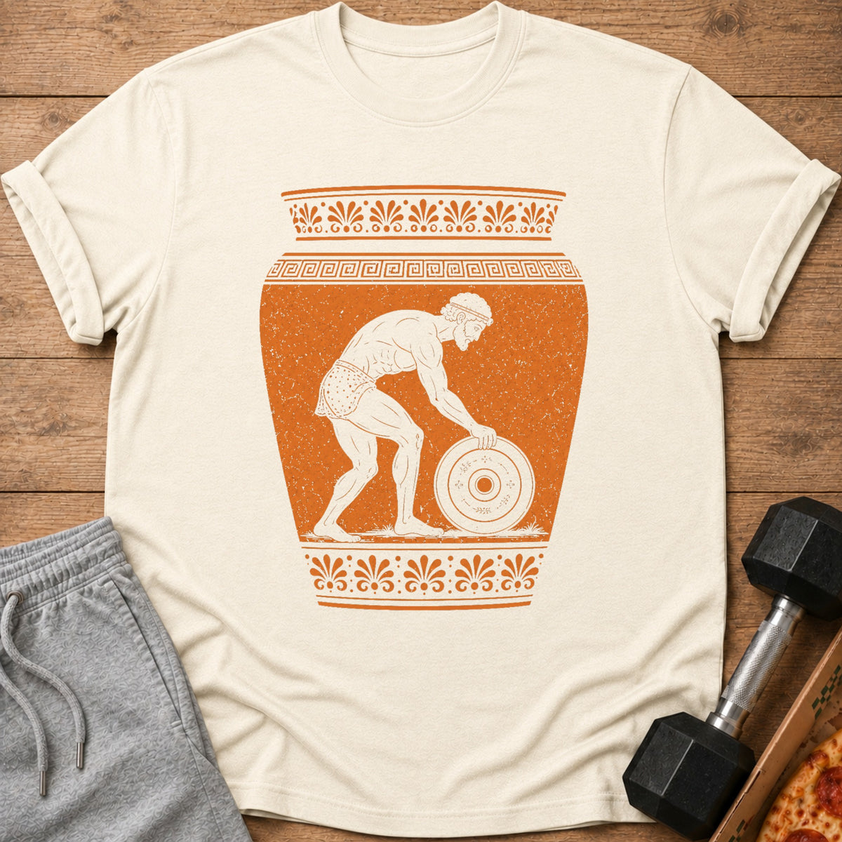 T-shirt with orange illustration of ancient Greek athlete lifting weight within a vase.