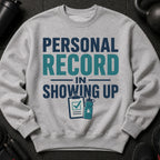 Grey sweatshirt with text "PERSONAL RECORD IN SHOWING UP" and icons.