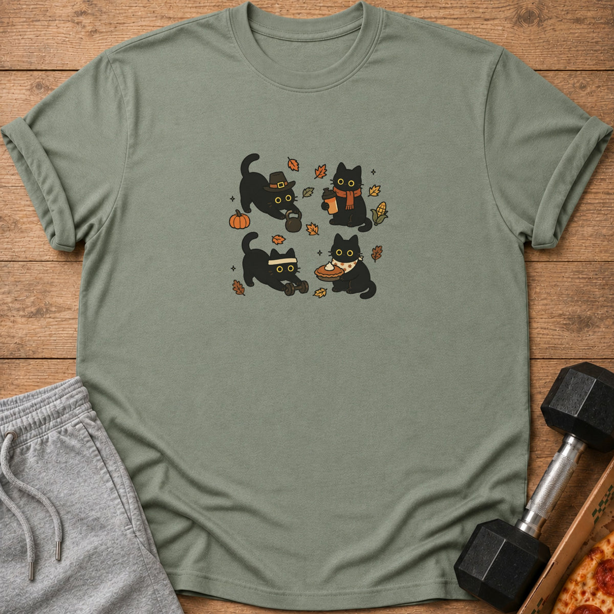 Four cartoon black cats with Thanksgiving and autumn themes on a green t-shirt.