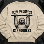Beige sweatshirt with black text and sloth graphic: "SLOW PROGRESS IS PROGRESS"