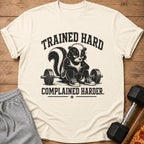 T-shirt with skunk character sitting by barbell and text "TRAINED HARD COMPLAINED HARDER."