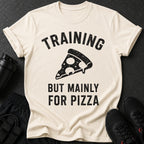 Cream t-shirt with black text "TRAINING BUT MAINLY FOR PIZZA" and pizza slice graphic.