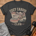T-shirt graphic with text "Cozy Cardio Club" featuring a sneaker, coffee cup, and dumbbell.