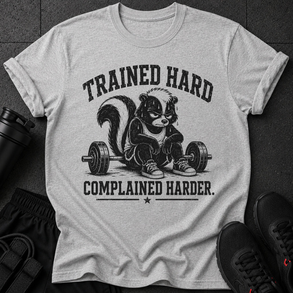 Grey t-shirt with a cartoon skunk sitting on a barbell, text reads "Trained Hard Complained Harder."
