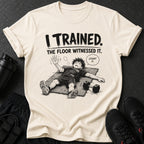 Shirt with "I TRAINED. THE FLOOR WITNESSED IT. COUNT IT." text and illustrated exhausted character.