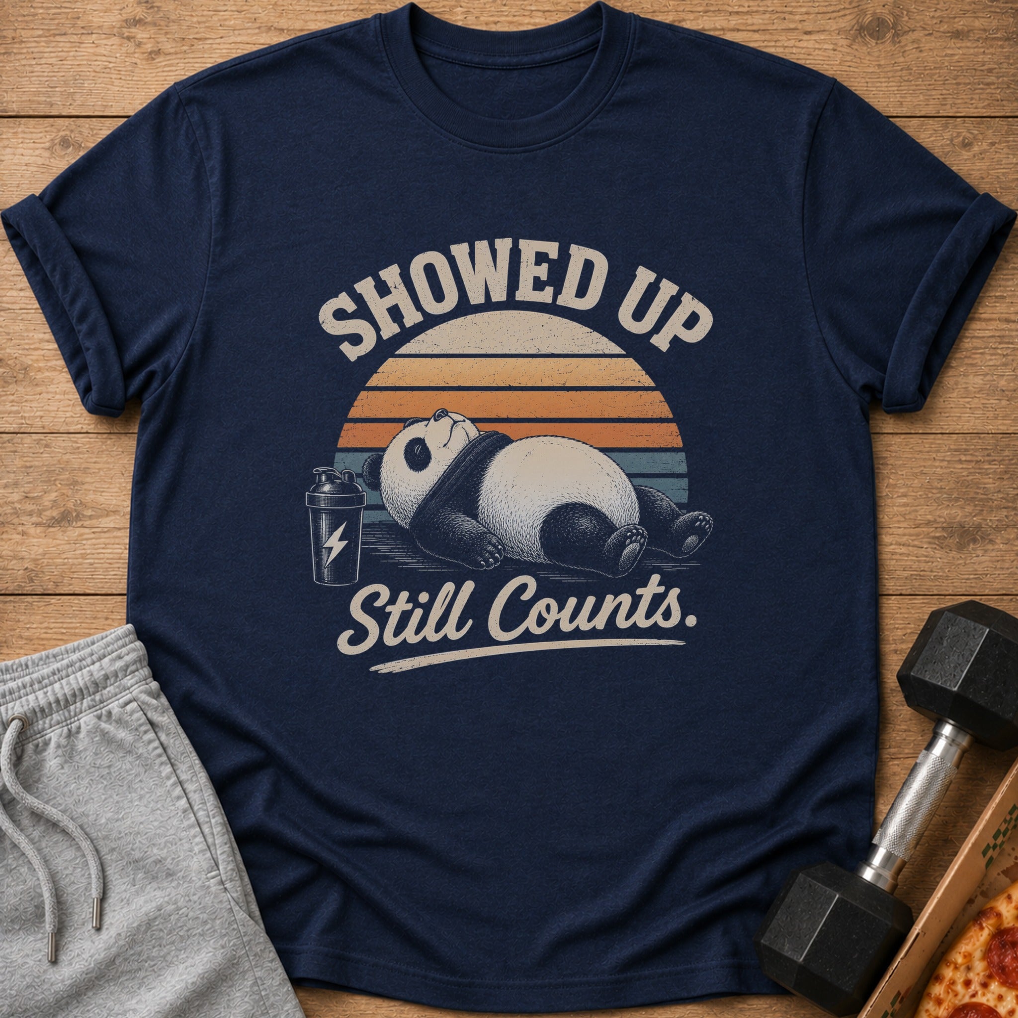 Navy t-shirt with a graphic of a panda sleeping, a shaker bottle, and text that says "Showed Up Still Counts."