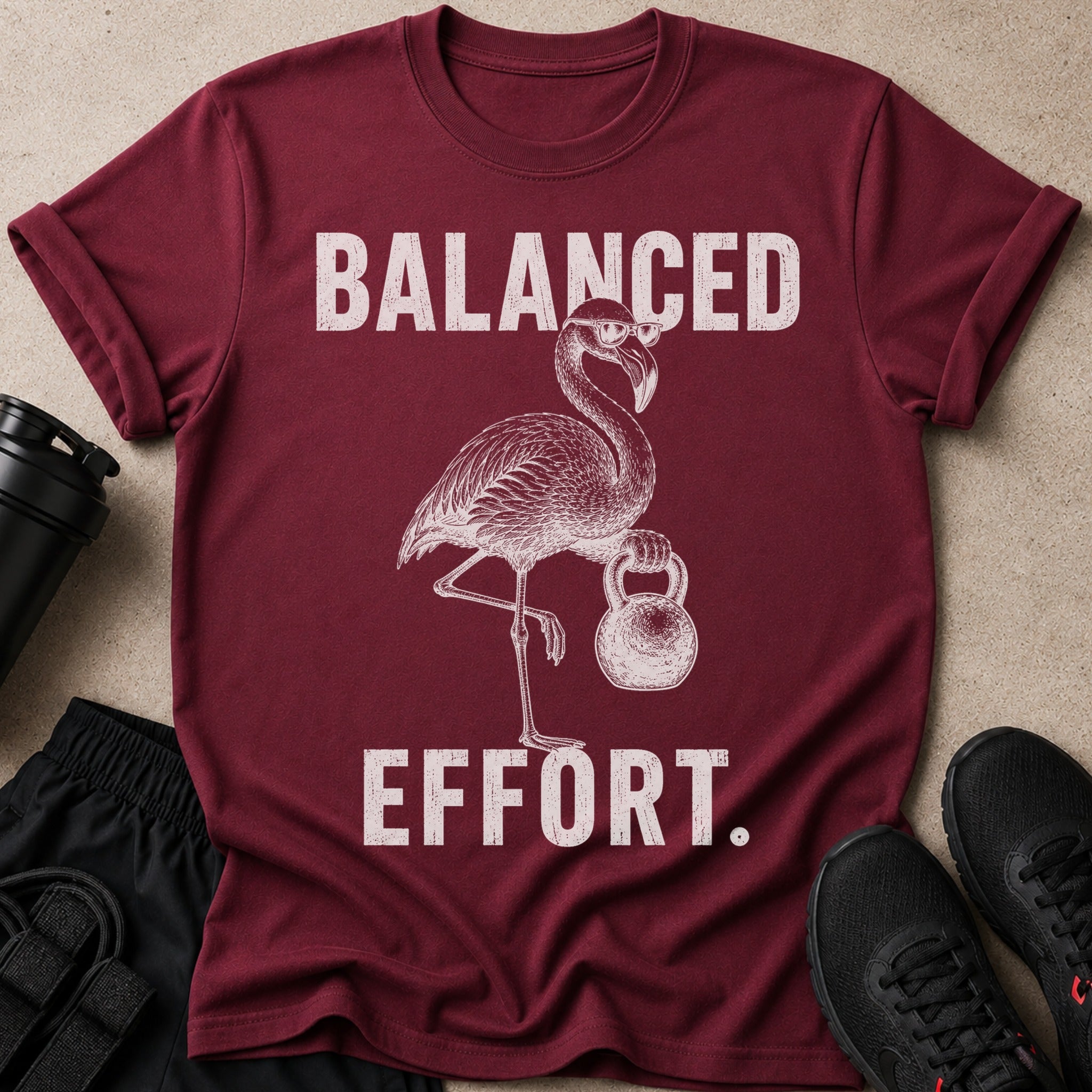 T-shirt with distressed graphic of a flamingo wearing glasses holding a kettlebell with text "BALANCED EFFORT."