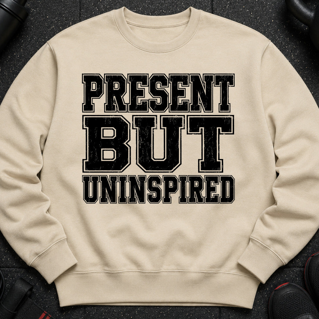 Light beige sweatshirt with distressed black text "PRESENT BUT UNINSPIRED".