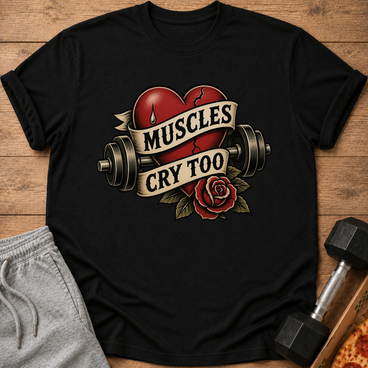 Black t-shirt with cracked heart, dumbbells, and text "Muscles Cry Too".