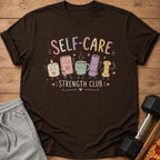 A brown t-shirt featuring a cute self-care illustration with the text Self-Care Strength Club.