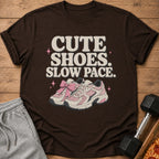 Brown t-shirt with pink sneakers, bow, and "Cute Shoes. Slow Pace." text.