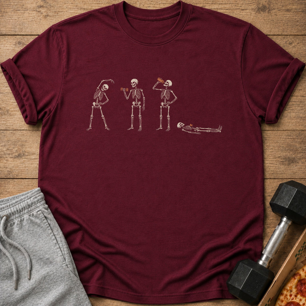 Maroon t-shirt with cream skeleton graphic performing exercises and drinking from a bottle.