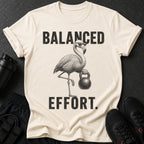 T-shirt with flamingo wearing sunglasses holding a kettlebell and text "BALANCED EFFORT."
