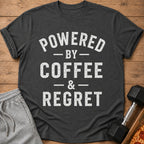 Dark grey t-shirt with white text: "POWERED BY COFFEE & REGRET".