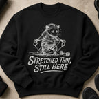 Black sweatshirt with distressed graphic of a rat stretching and text "Stretched Thin, Still Here".