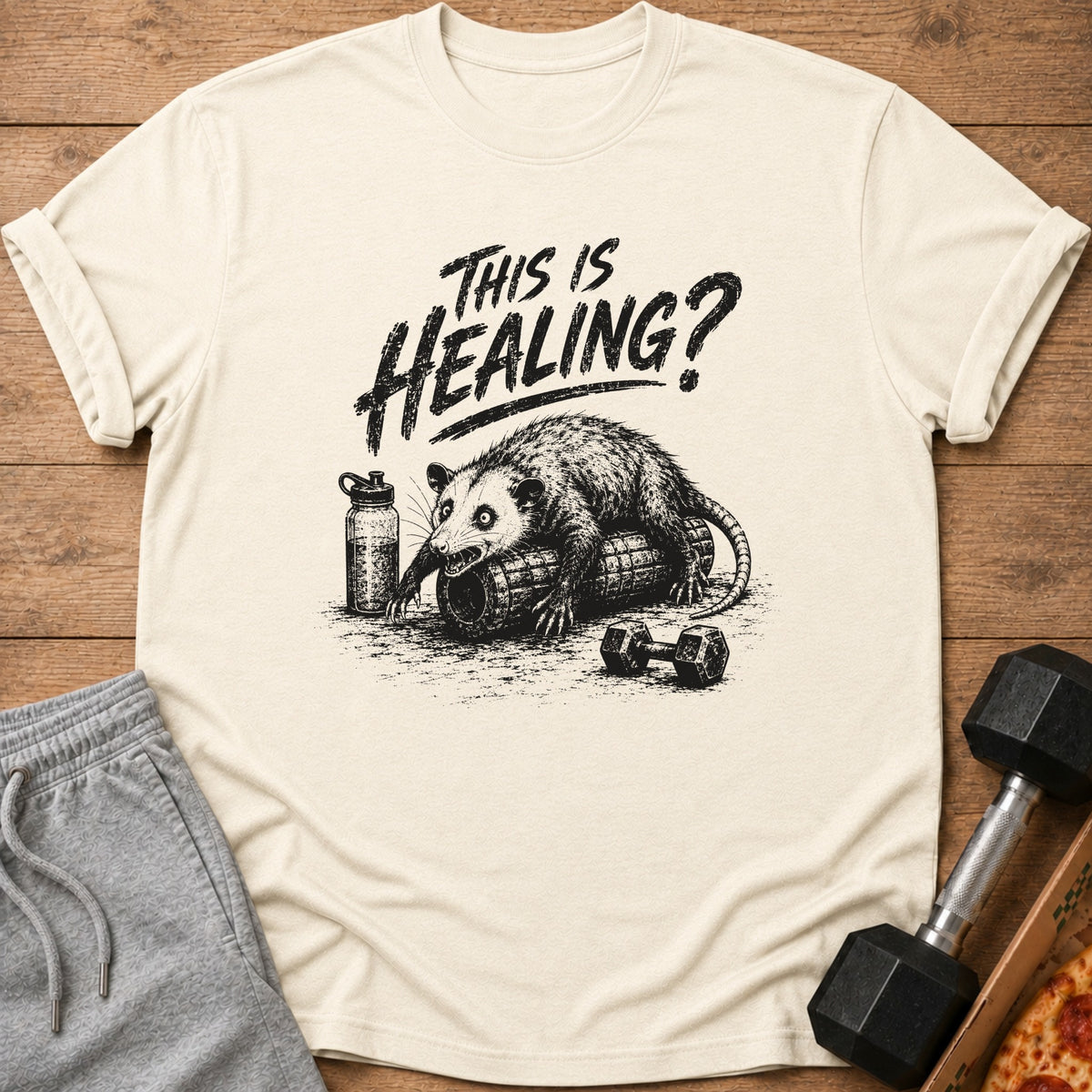 Opossum on foam roller with dumbbell, water bottle, and text "This is HEALING?".