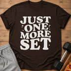 Brown t-shirt with white text "JUST ONE MORE SET" and gym accessories.