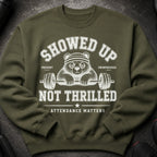 Green sweatshirt with graphic of unenthusiastic panda holding barbell, saying "Showed Up Not Thrilled Attendance Matters".