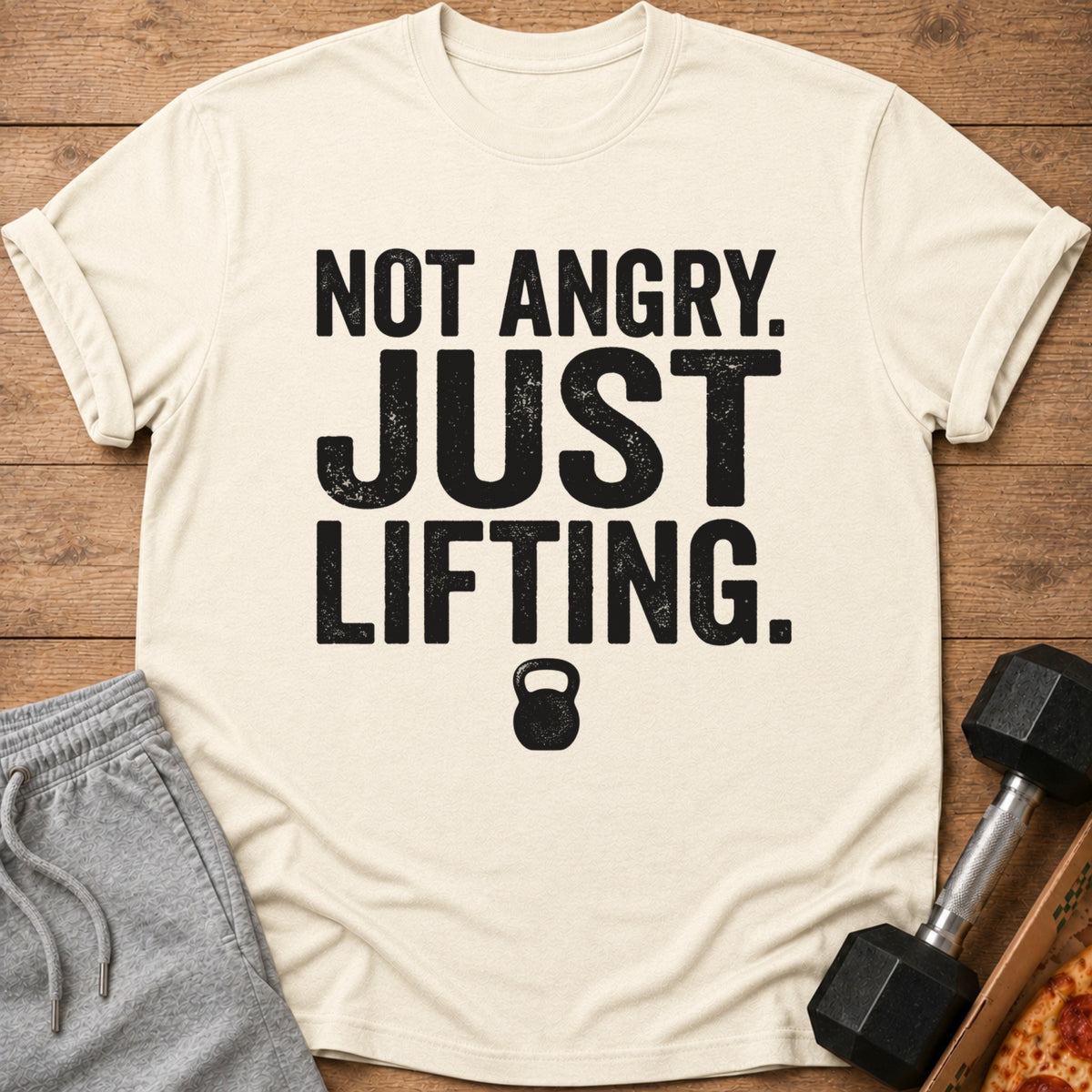 Cream t-shirt with text "NOT ANGRY. JUST LIFTING." and a kettlebell graphic.