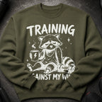Green sweatshirt with raccoon, coffee, and dumbbells graphic: "TRAINING AGAINST MY WILL".