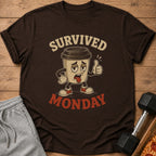 Brown t-shirt with cartoon coffee cup saying "Survived Monday" and giving thumbs up.
