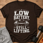 Brown t-shirt with "LOW BATTERY. STILL LIFTING." text and barbell graphic.