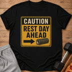 Black t-shirt with distressed yellow sign reading "CAUTION REST DAY AHEAD" and a foam roller icon.
