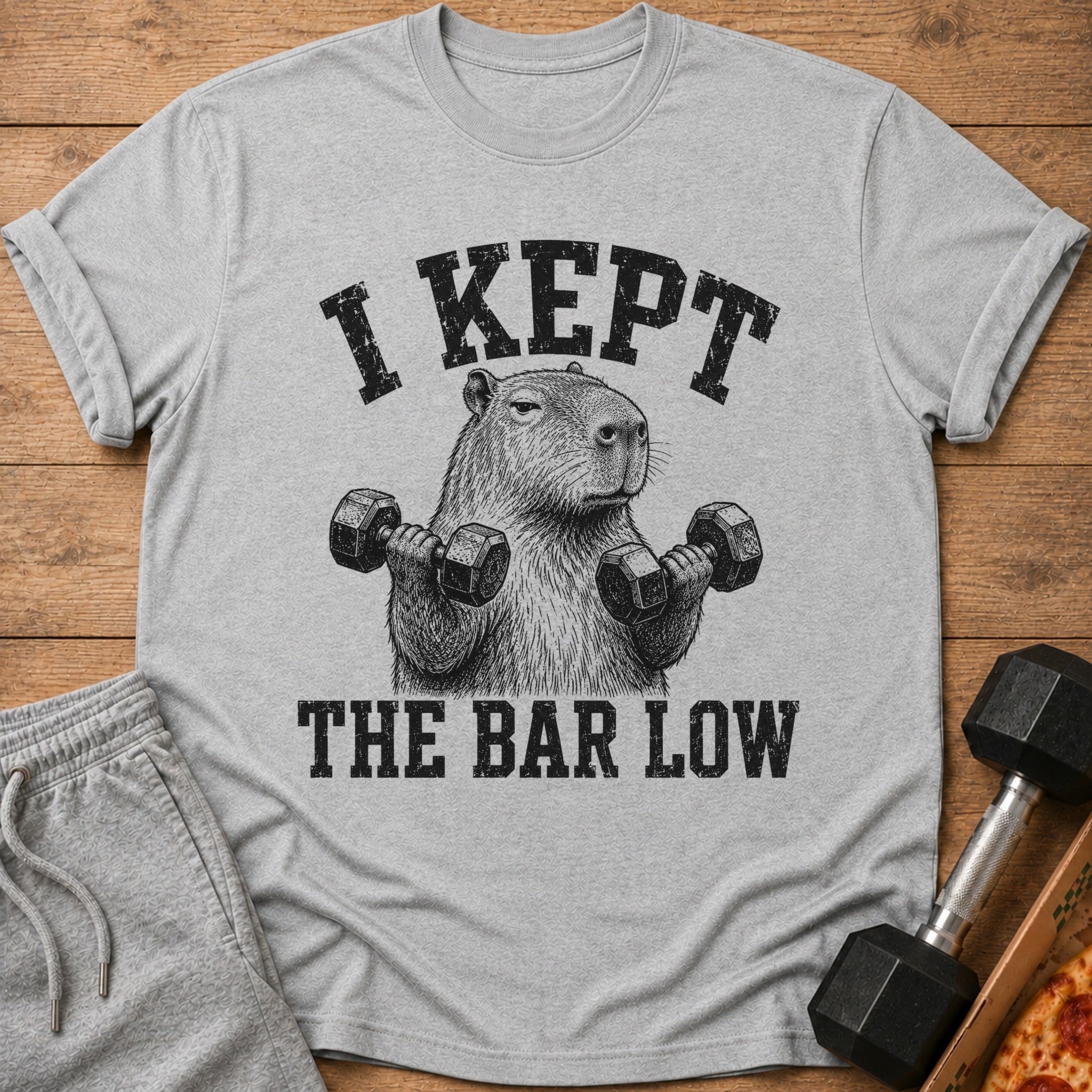 Gray t-shirt with capybara lifting dumbbells, text "I kept the bar low".