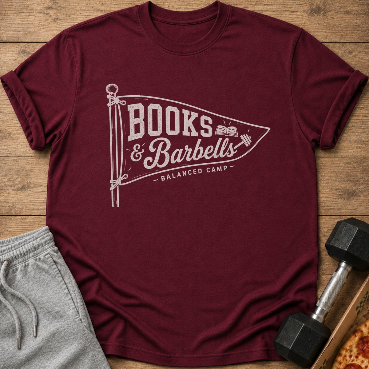 Maroon t-shirt with "Books & Barbells" logo, alongside sweatpants and a dumbbell.