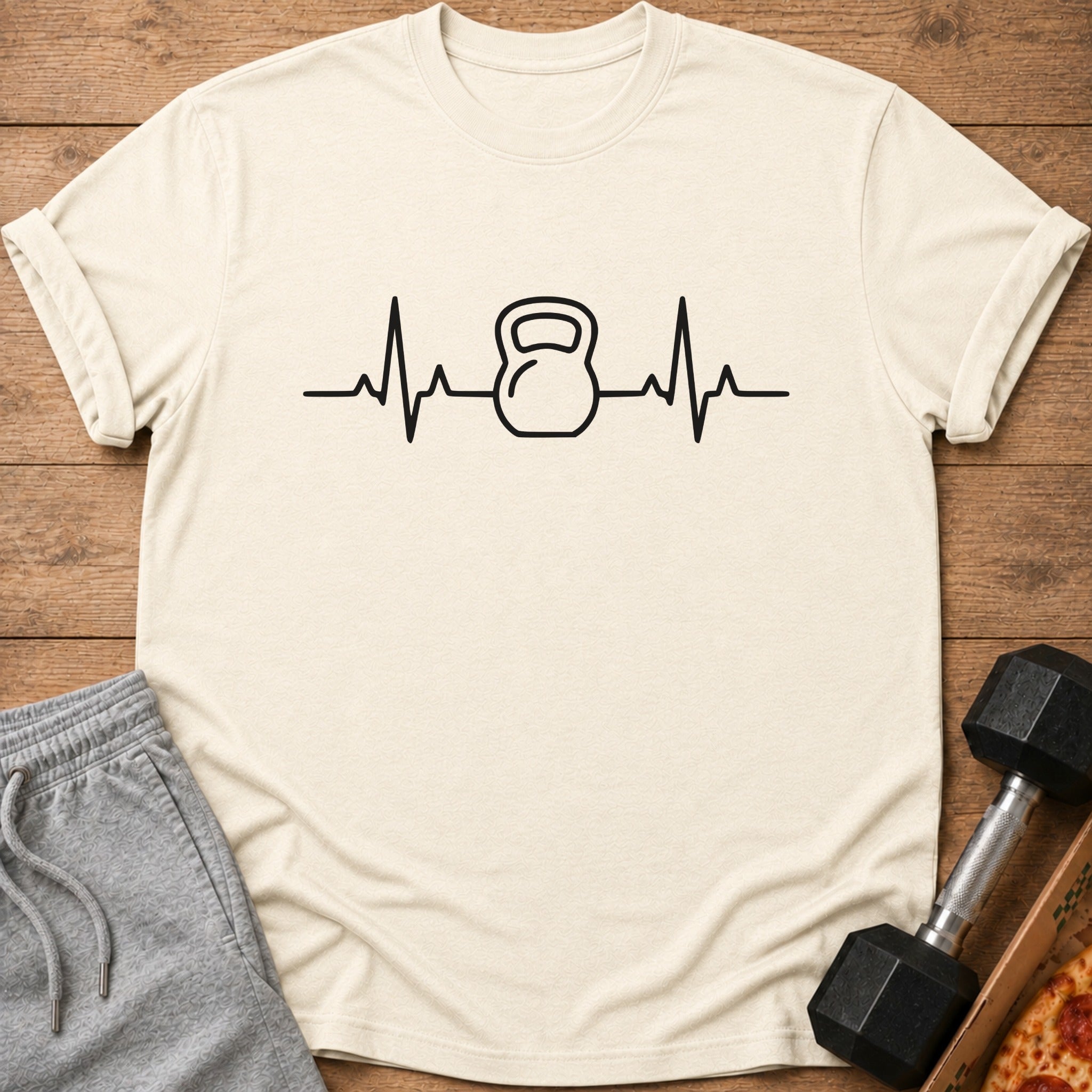 Cream t-shirt with black kettlebell and heartbeat graphic.