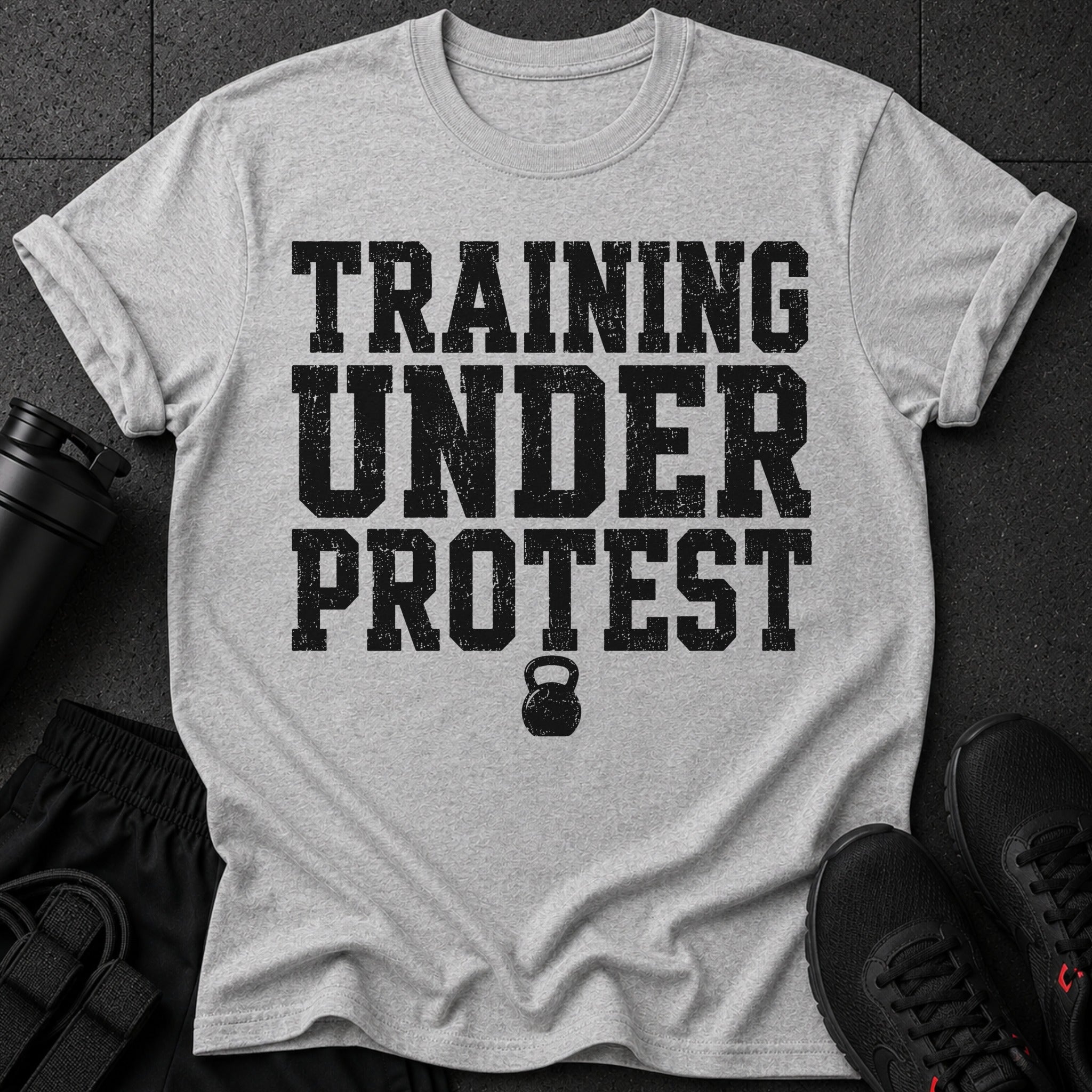 Grey t-shirt with black distressed text "TRAINING UNDER PROTEST" and a kettlebell graphic.