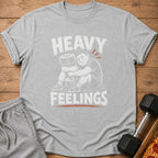 Grey t-shirt with white text "HEAVY FEELINGS" and an illustration of a person hugging a weight.
