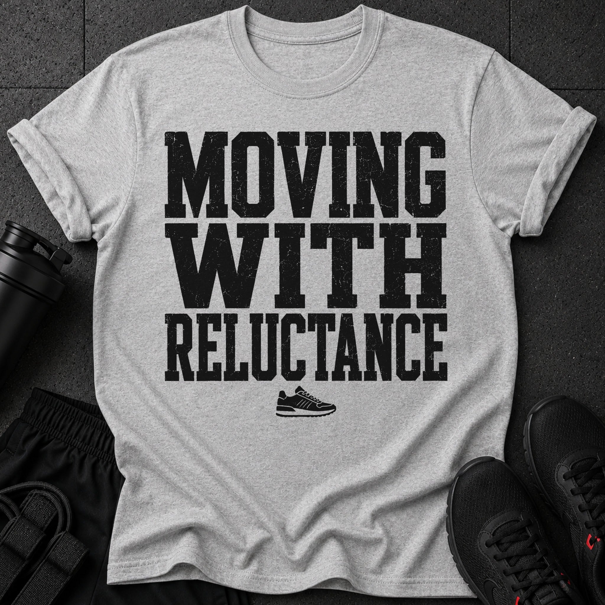 Grey t-shirt with black distressed text "MOVING WITH RELUCTANCE" and a sneaker graphic.