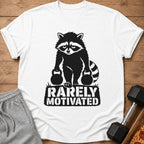 White t-shirt with a black graphic of a raccoon holding weights and text "RARELY MOTIVATED."