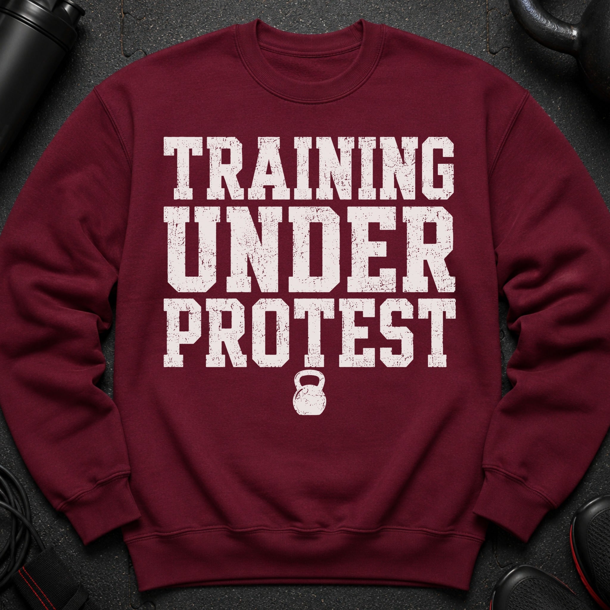 Maroon sweatshirt with "TRAINING UNDER PROTEST" and kettlebell graphic.