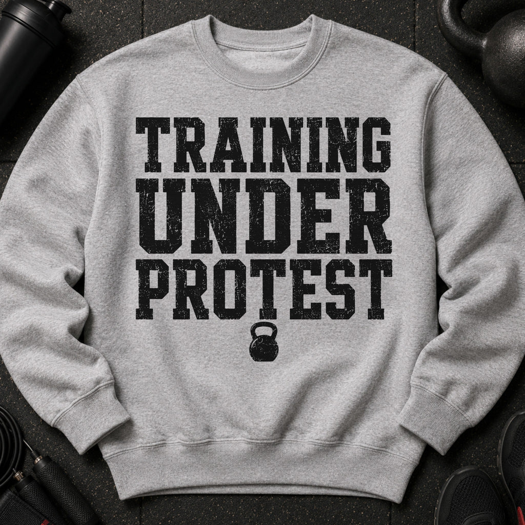 Grey crewneck sweatshirt with distressed black text "TRAINING UNDER PROTEST" and kettlebell graphic.